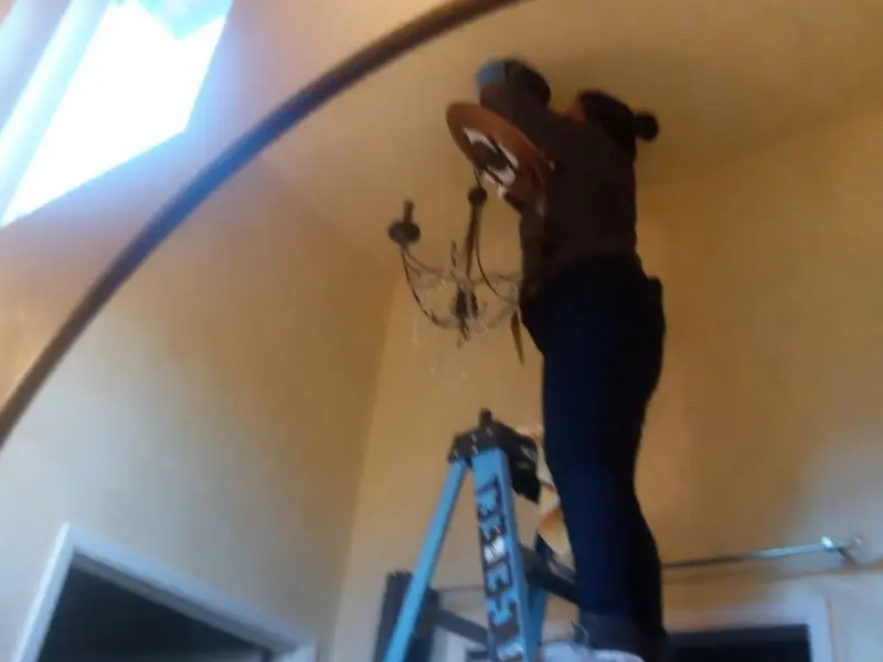 Electrician installing a chandelier in a Spencer residence